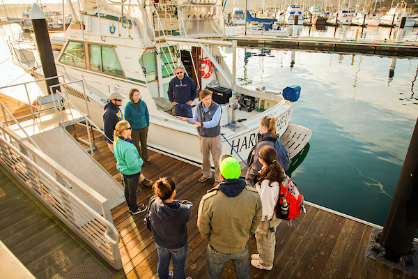 Group of Marine Science students and instructor on the docks in Monterey and in front of a boat